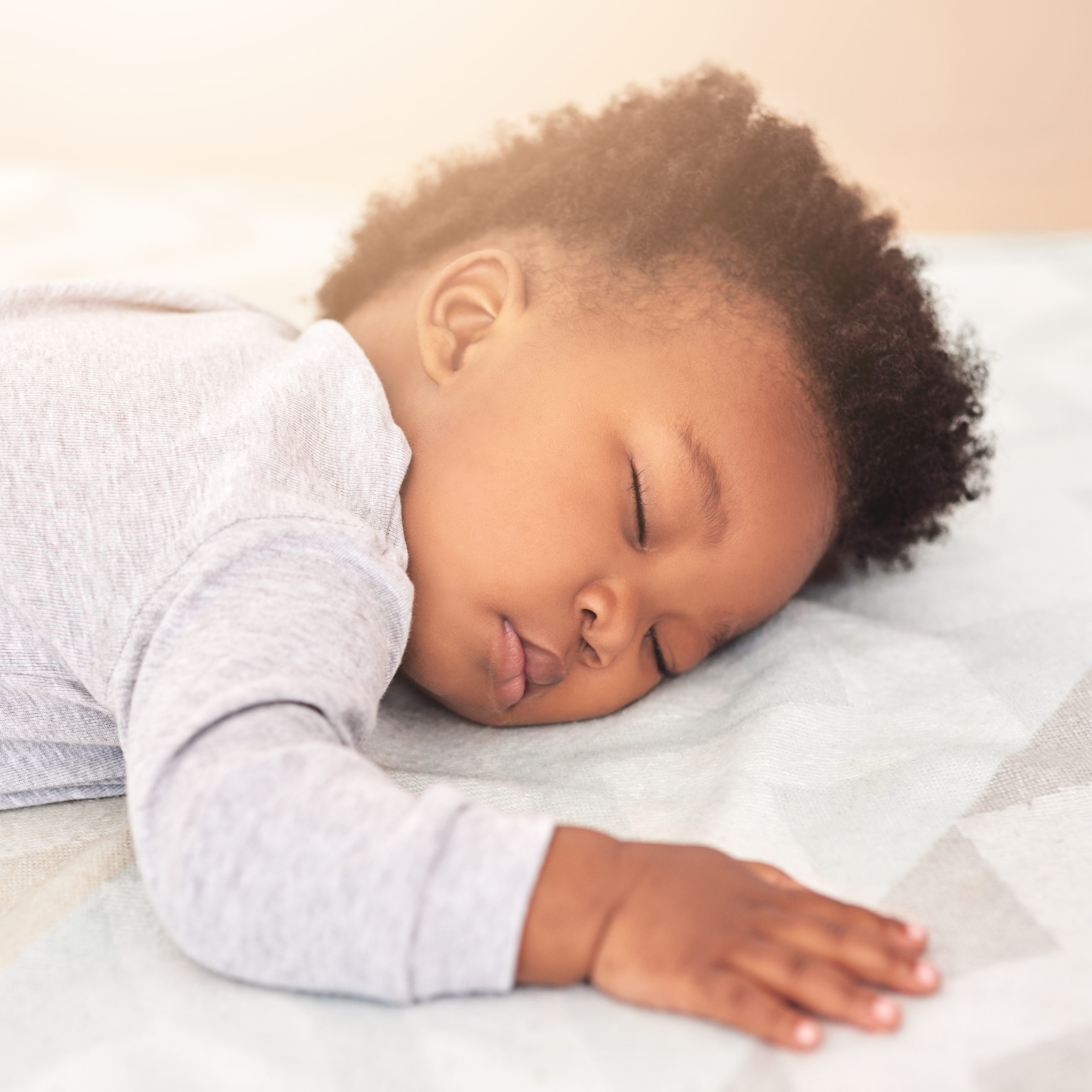 Shot of a little baby boy sleeping on his tummy on a bed